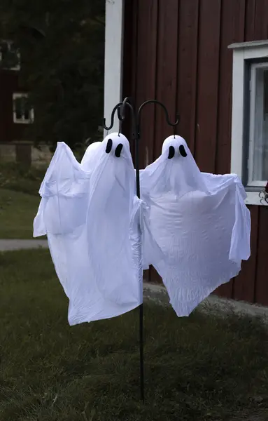 Helppo halloween-askartelu pihalle: valkoisesta kankaasta tehdyt haamukoristeet roikkuvat puutarhatelineessä.