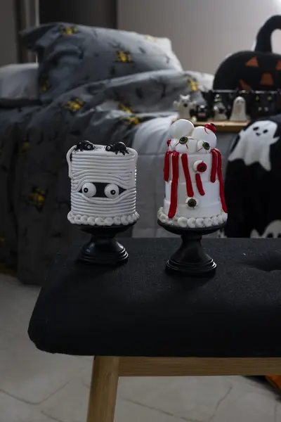 Muumioaiheiset halloween-koristeet tuolilla, taustalla halloween-kuvioitu vuodevaatetus ja kurpitsakoriste.