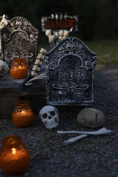 Koristeellinen hautakivi, pääkallo ja lyhdyt Halloween-aiheisessa pihasisustuksessa.