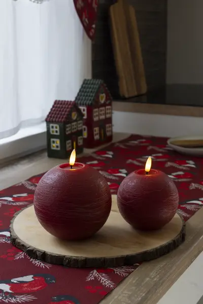 Punaiset pallokynttilät ja jouluaiheinen kaitaliina tuovat lämpöä keittiön kattaukseen.